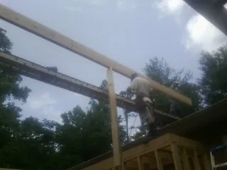 Carpenter setting a ridge beam over a new addition frame — Ice Dam Removal by Roofing Brothers in Delong