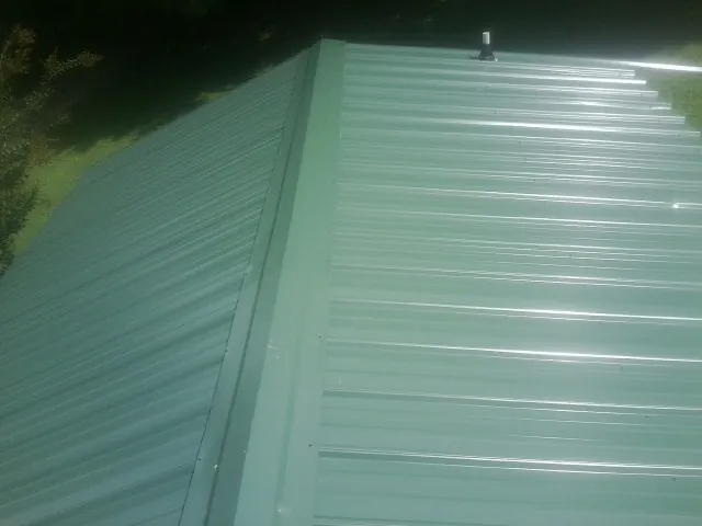 New green metal panels meeting at the ridge of a roof in Delong