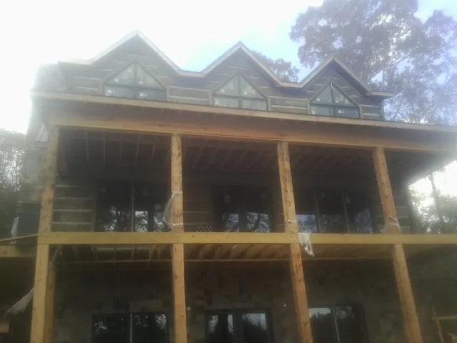 Dormers and porch framing on a large log home under construction — Roof Coating work by our crew in Delong