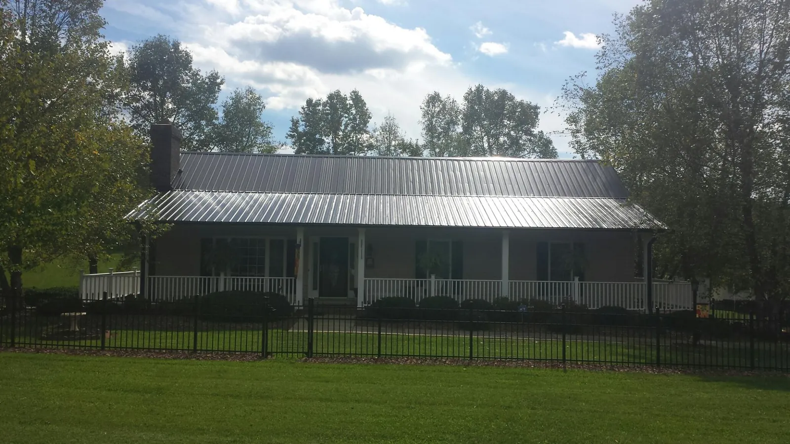 Gray metal roof on a brick ranch with a full width front porch — Gutter Guard Installation work by our crew in Delong