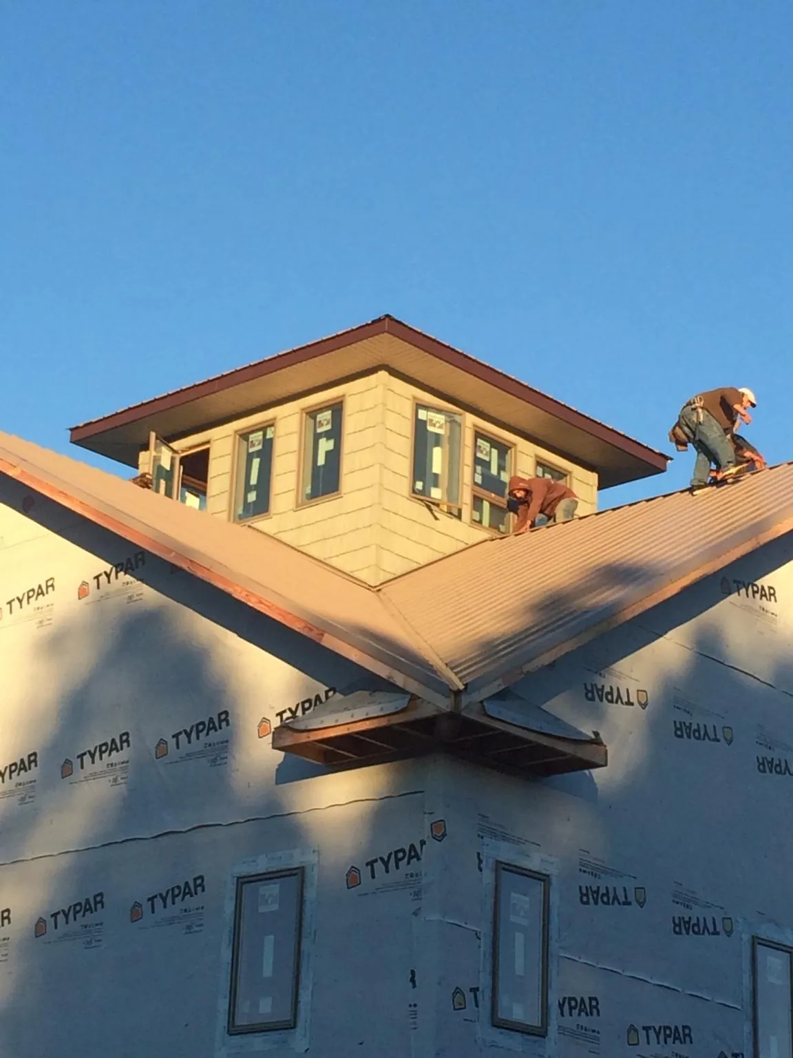 Roofers working around a rooftop cupola on a new metal roof at sunset — Roof Waterproofing in Delong by Roofing Brothers
